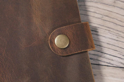 Close-up of a brown leather strap with a metal buckle on a wooden surface